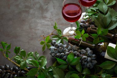 Natürmort kadehlerin, şişe, üzüm ve yaprakları kahverengi ahşap masa