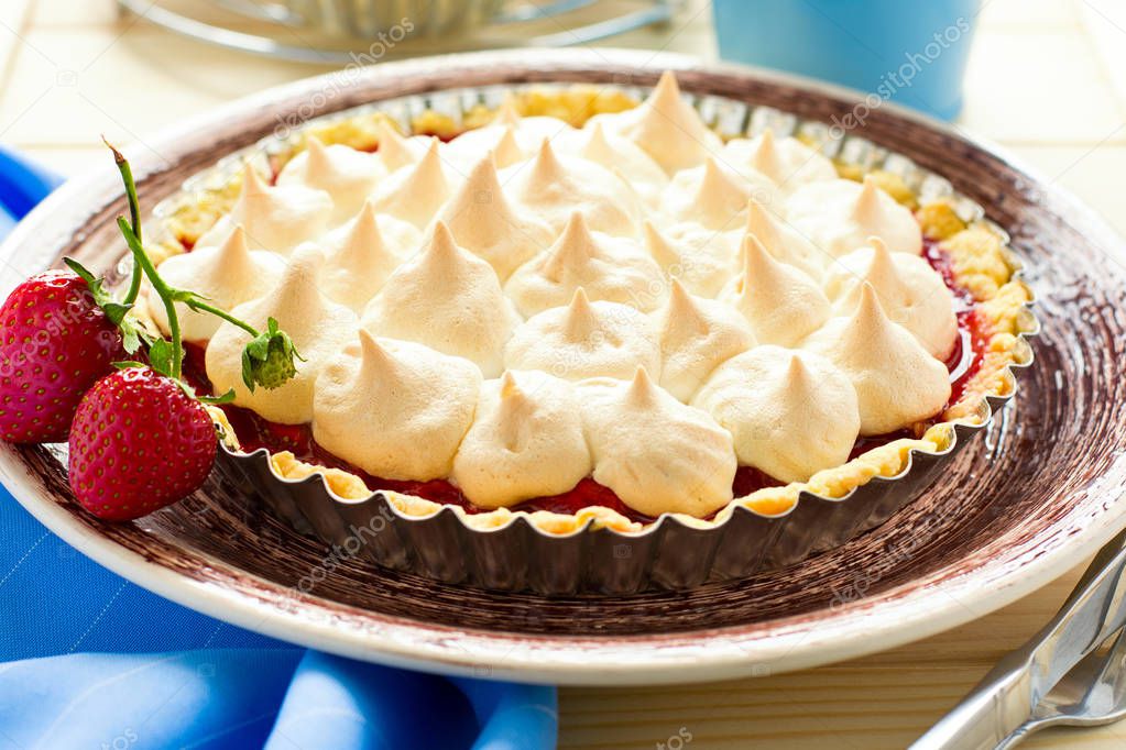 Strawberry tart with meringue on brown plate. Selective focus