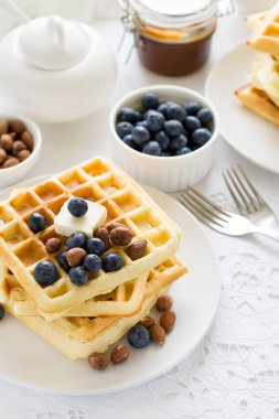 Sağlıklı kahvaltı. Tereyağı, yaban mersini ve fındık üzerinde beyaz masa örtüsü ile Belçika waffle. Seçici odak