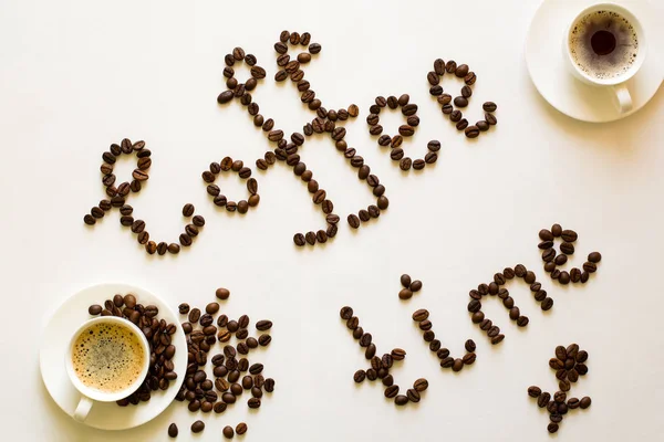 Two cups of espresso and Coffee time text from beans on white table. Top view