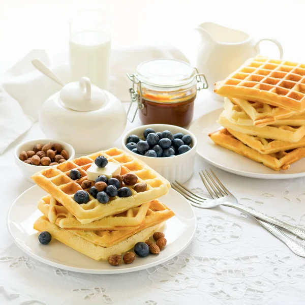 Healthy breakfast. Belgian waffles with butter, blueberry and nuts on white tablecloth. Selective focus