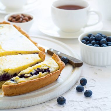 Çay saati. Ev yapımı yaban mersinli cheesecake, bardak çay, fındık ve berry beyaz masa örtüsü