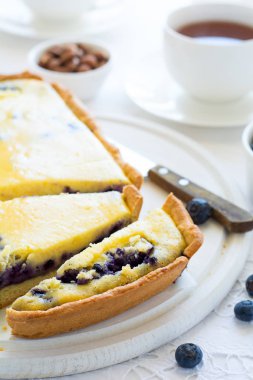 Çay saati. Ev yapımı yaban mersinli cheesecake, bardak çay, fındık ve berry beyaz masa örtüsü