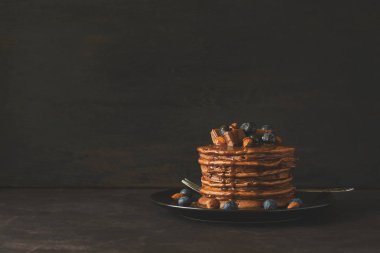 Krema, yaban mersini, badem, fındık ve çikolata parçaları ile çikolatalı krep yığını. Seçici odak. Tonda