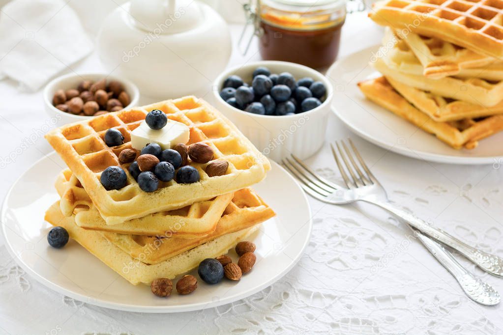Healthy breakfast. Belgian waffles with butter, blueberry and nuts on white tablecloth. Selective focus