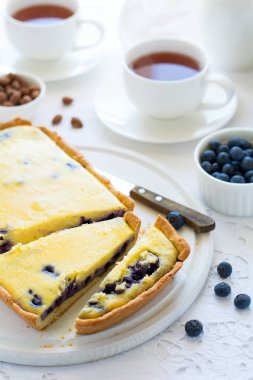 Çay saati. Ev yapımı blueberryy cheesecake, bardak çay, fındık ve berry beyaz masa örtüsü