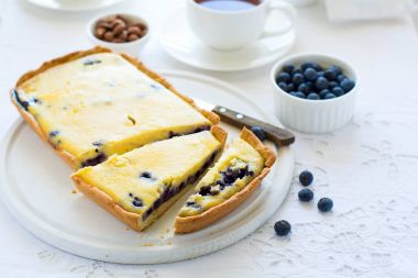 Çay saati. Ev yapımı yaban mersinli cheesecake, bardak çay, fındık ve berry beyaz masa örtüsü