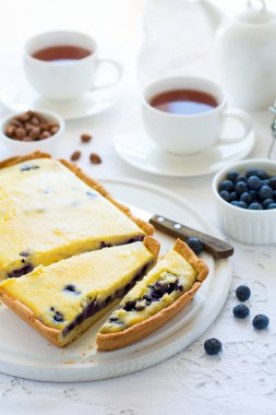 Çay saati. Ev yapımı blueberryy cheesecake, bardak çay, fındık ve berry beyaz masa örtüsü