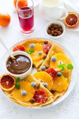 Fransız krep. Krep Suzette karamel, portakal, yaban mersini, badem ve fındık üzerinde beyaz masa örtüsü