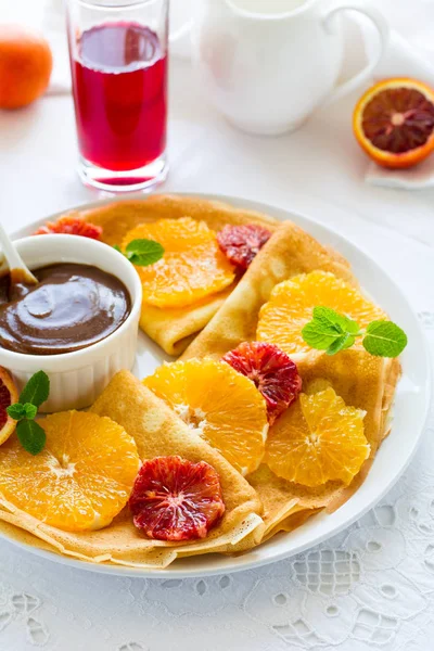 Fransız krep. Krep Suzette karamel, portakal, yaban mersini, badem ve fındık üzerinde beyaz masa örtüsü