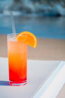 Arka plan mavi su ile sahilde renkli kokteyller gözlüklü. Tonda