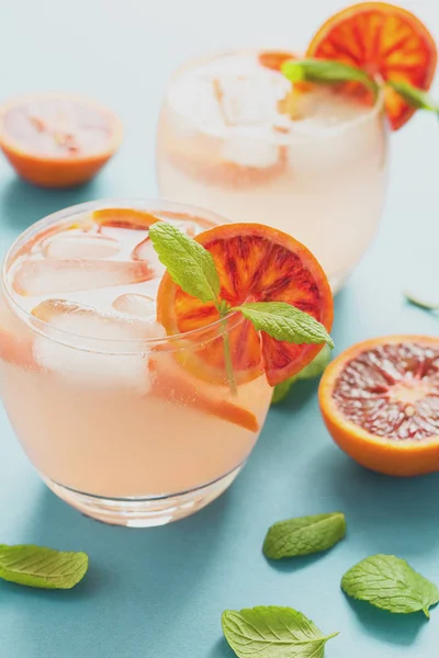 Blood orange cocktail with slices of orange on turquoise background. Toned
