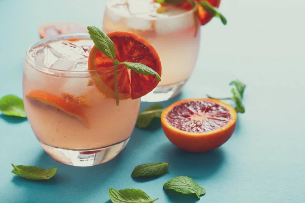 Blood orange cocktail with slices of orange on turquoise background. Toned