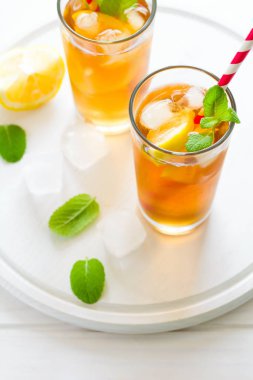 Beyaz ahşap zemin üzerine nane ve limon dilimleri ile buzlu çay bardak