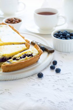 Çay saati. Ev yapımı yaban mersinli cheesecake, bardak çay, fındık ve berry beyaz masa örtüsü