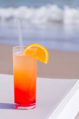 Arka plan mavi su ile sahilde renkli kokteyller gözlüklü. Tonda