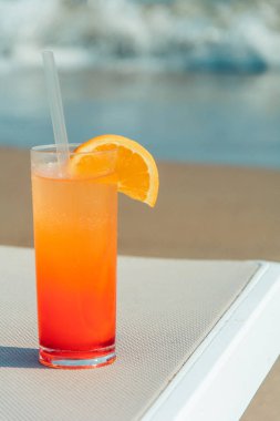 Arka plan mavi su ile sahilde renkli kokteyller gözlüklü. Tonda