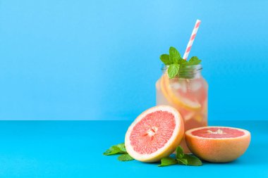 Kavanoz greyfurt limonata ile dekore edilmiş buz ve nane mavi kağıt arka plan üzerinde.