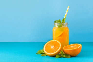 Kavanoz turuncu limonata ile dekore edilmiş buz ve nane mavi kağıt arka plan üzerinde.