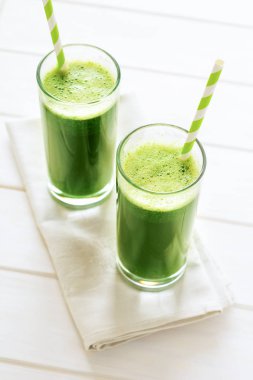 Ispanak, elma ve salatalık bir kavanoz Beyaz ahşap masa üzerinde kırmızı saman ile yapılan sağlıklı yeşil smoothie