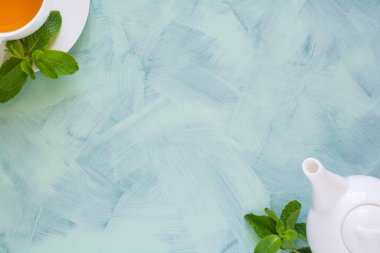 Çay kavramı. Çaydanlık ve bardak yeşil bitki çayı ile nane yaprakları ahşap zemin üzerine dekore edilmiştir. Üstten Görünüm. Uzay kopyalayın. Düz yatıyordu