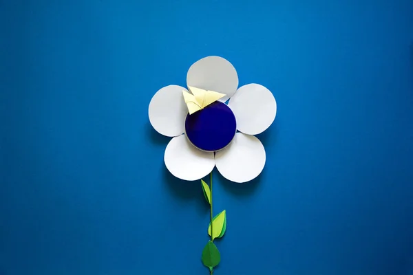 Frauenhände mit Papierblumen auf blauem Papier-Hintergrund. Papierschnitt. Ansicht von oben — Stockfoto