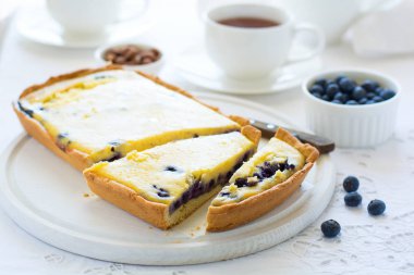 Çay saati. Ev yapımı yaban mersinli cheesecake, bardak çay, fındık ve berry beyaz masa örtüsü