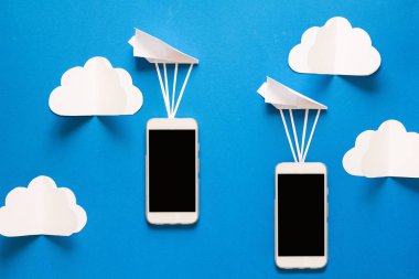 Veri aktarım kavramı. İleti gönderme. İki hareket eden smartphones ve mavi arka plan üzerinde kağıt airpaplanes. Origami. Kağıt kesiği.