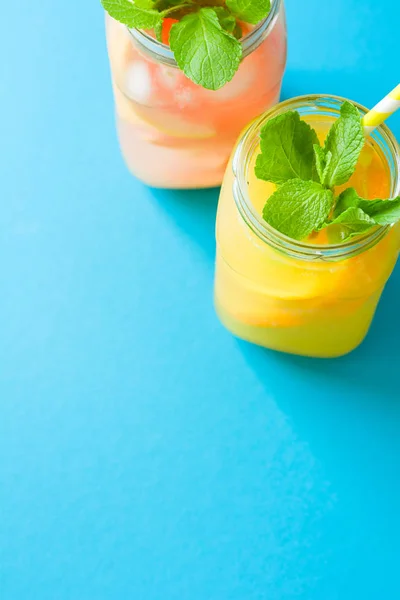 Butelki Pomarańczowy Grejpfrutowy Lemoniady Urządzone Lodu Mięta Tle Niebieski Papier — Zdjęcie stockowe