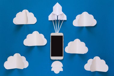 Başlamak yukarıya ya da bağlantı kavramı hızlı. Mavi gökyüzü bulutlar ile akıllı telefon ile denize indirmek kağıt roket. Origami. Kağıt kesiği. Üstten Görünüm