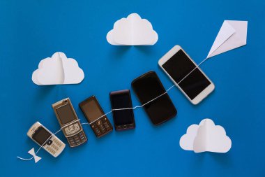 Teknoloji evrim kavramı. Vintage ve mavi gökyüzü kağıt uçurtma uçan yeni telefonları. 