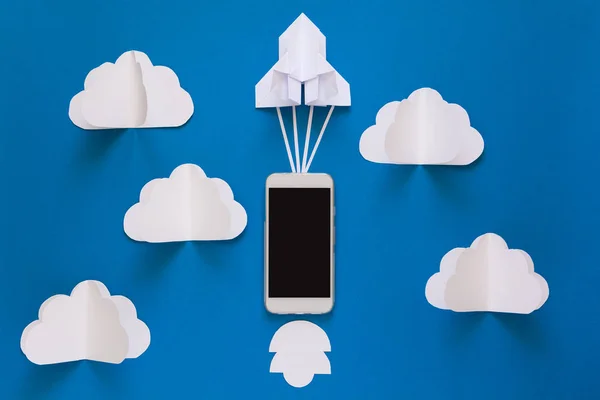 Başlamak yukarıya ya da bağlantı kavramı hızlı. Mavi gökyüzü bulutlar ile akıllı telefon ile denize indirmek kağıt roket. Origami. Kağıt kesiği. Üstten Görünüm