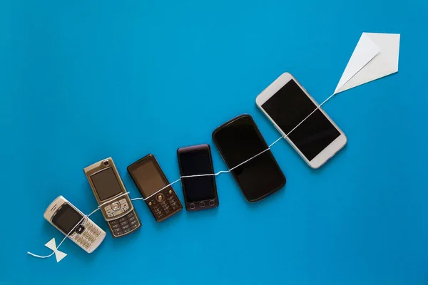 Teknoloji evrim kavramı. Vintage ve mavi gökyüzü kağıt uçurtma uçan yeni telefonları. 