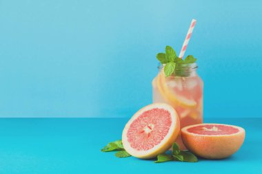 Kavanoz greyfurt limonata ile dekore edilmiş buz ve nane mavi kağıt arka plan üzerinde. Tonda