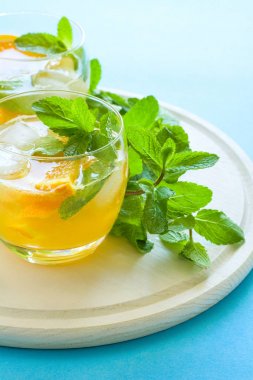 Dilim portakal, buz ve mavi zemin üzerine nane ile turuncu limonata.