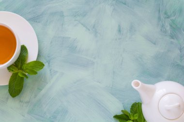 Çay kavramı. Çaydanlık ve bardak yeşil bitki çayı ile nane yaprakları ahşap zemin üzerine dekore edilmiştir. Üstten Görünüm. Uzay kopyalayın. Düz yatıyordu
