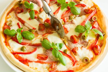 Taze pizza domates, mozzarella peyniri, kırmızı biber ve zeytin ile dekore edilmiş fesleğen yaprakları beyaz tahta masada. Yakın çekim