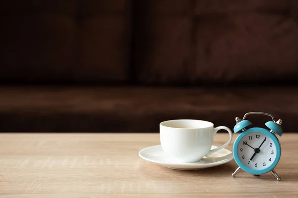 Taza Café Reloj Mesa Madera Contra Sofá Desenfocado Con Almohadas — Foto de Stock