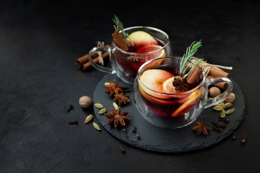 İki bardak noel şarabı ya da baharatlı gluhwein ve koyu ahşap arka planda limon dilimleri ve odandan çıkarılmış ışıklar. Noel veya Yeni Yıl Kutlama Konsepti