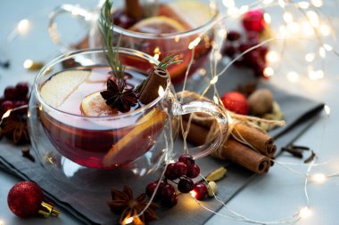 İki bardak noel şarabı ya da baharatlı gluhwein ve gri ahşap arka planda limon dilimleri ve sönmüş ışıklar. Noel veya Yeni Yıl Kutlama Konsepti