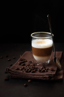 Koyu ahşap masadaki termo cam kahve fincanının önü. Sabah içeceği.