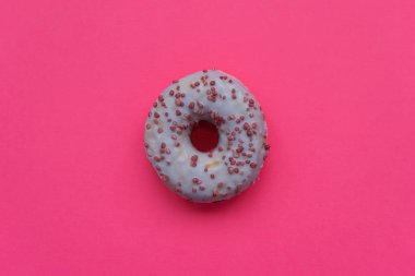 Mor donut, pembe arka planda renkli serpiştirilmiş. Düz yatıyordu. Üst Manzara. Sağlıksız yiyecekler