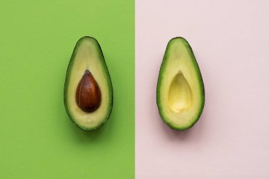 Avokado yarım pembe ve yeşil arka plan. Üst Manzara. Minimum yaz yemeği konsepti. Düz yatıyordu