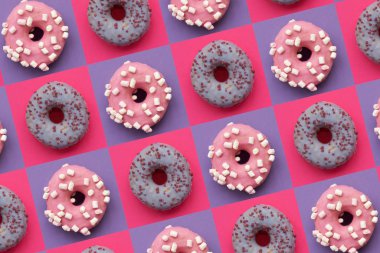 Donut desenleri dekore edilmiş şekerlemeler ve kare pembe ve mor arkaplanda renkli şekerlemeler. Düz yatıyordu. Üst Manzara. Sağlıksız yiyecekler