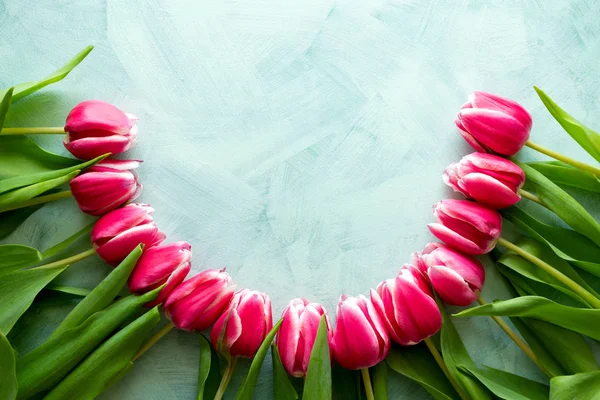 Fresh pink tulips on turquoise background. Top view. Flat lay. Copy space. Valentines day, mothers day or birthday celebration concept