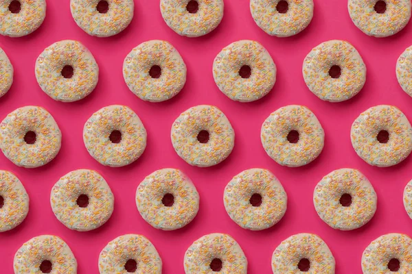 ピンクを基調にカラフルなスプリンクルで装飾された釉ドーナツからのパターン 平置きだ最上階だ不健康な食べ物 — ストック写真