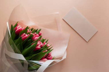 Pembe arka planda boş kart olan bir buket pembe lale. Sevgililer Günü ya da Anneler Günü konsepti. Üst Manzara. Düz yatıyordu. Boşluğu kopyala.