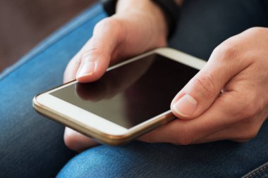 Genç yetişkin akıllı telefon kullanıyor ve ekranda dokunuyor. Yumuşak odaklanma. Akıllı teknoloji