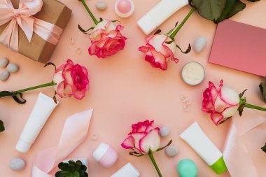Taze pembe güllerden, kozmetik tüplerden, hediye kutusundan ve pembe arka plandaki tebrik kartından çerçeveler. Üst Manzara. Düz yatıyordu. Uzayı kopyala Sevgililer günü, anneler günü, doğum günü kutlaması ya da temiz güzellik konsepti