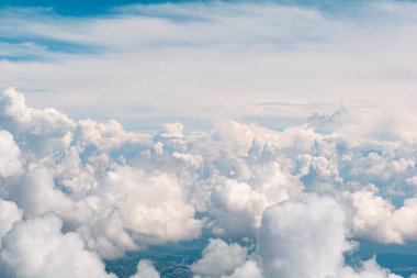 Şehrin üzerinde kabarık bulutlar. Uçak penceresinden hava görüntüsü
